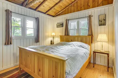a bedroom with a wooden bed and two windows at Boat, Hike and Fish Rustic Greenwood Retreat in Greentown