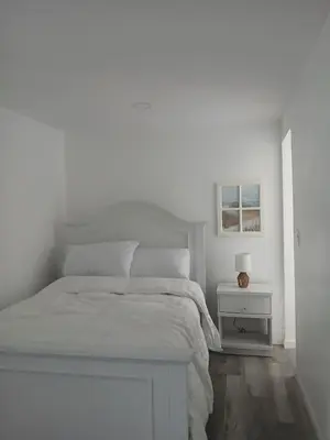 a white bedroom with a bed and a night stand at Labelle in Wilkes-Barre