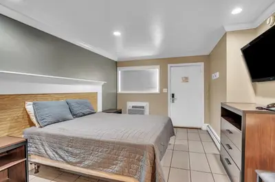 a bedroom with a bed and a flat screen tv at Bentley Motel in Linden