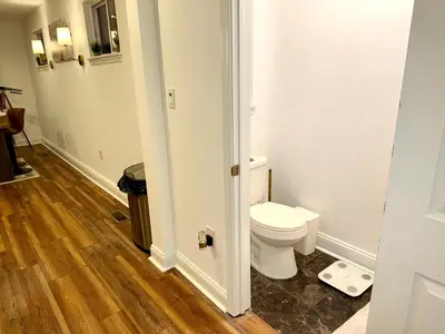 a bathroom with a toilet and a wooden floor at Spacious Private Ensuite, With Private Bath, Outdoor Space, Workstation, Gym, & All Utilities Included in Point Breeze Home in Philadelphia