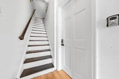 a hallway with a white door and a staircase at Quiet Retreat 10 Min to NYC Train & free Parking in Bayonne
