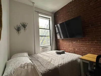 a bedroom with a bed and a brick wall at The Marquee House in New York