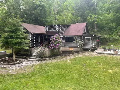 a small log cabin with flowers in front of it at Stony Creek Lodge in East Stroudsburg