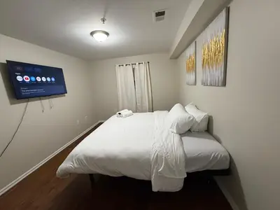 a bedroom with a white bed with a tv on the wall at Charming Large 3 beds-2 bath Newark EWR NYC in Newark