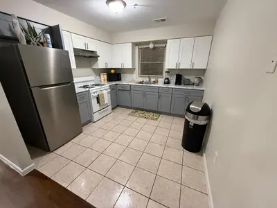 a kitchen with a stainless steel refrigerator and a tile floor at Charming Large 3 beds-2 bath Newark EWR NYC in Newark