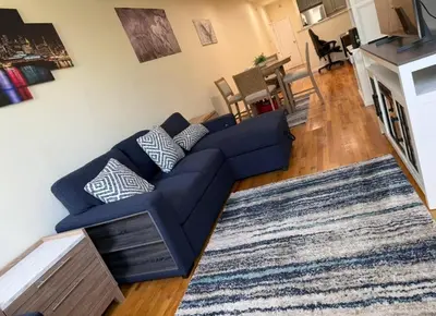 a living room with a blue couch and a rug at Weehawken Apartment NYC Skyline in Weehawken