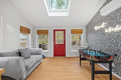 a living room with a table and a red door at Pocono Lake Escape, includes Golf Cart, Firepit in Pocono Lake