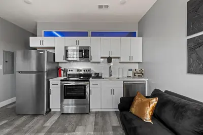 a kitchen with white cabinets and a black couch at Lunar Escape 1 Bd Near Zoo, Rocky Steps & Downtown in Philadelphia