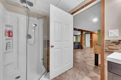 a bathroom with a shower and a white door at Secluded Log Cabin with Hot Tub Fire Pit Game Room in Newfoundland