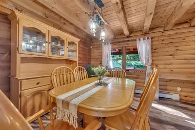 a dining room with a wooden table and chairs at Secluded Log Cabin with Hot Tub Fire Pit Game Room in Newfoundland