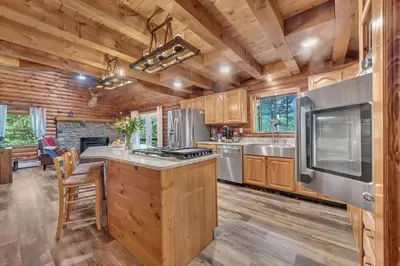 a kitchen with wooden cabinets and a stove top oven at Secluded Log Cabin with Hot Tub Fire Pit Game Room in Newfoundland