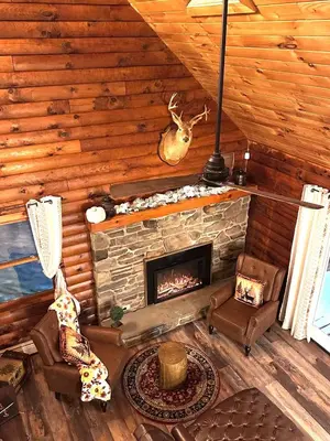 a living room with a fireplace in a log cabin at Secluded Log Cabin with Hot Tub Fire Pit Game Room in Newfoundland
