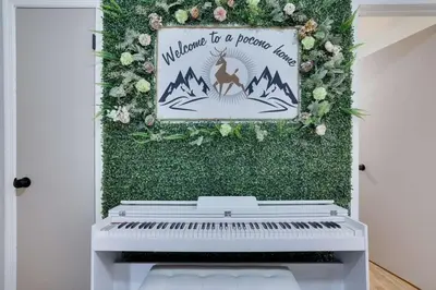 a white piano in front of a green wall with a sign at The Playhouse Retreat Large Game Room Fire Pit in Tobyhanna