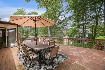 a wooden table with an umbrella on a deck at The Playhouse Retreat Large Game Room Fire Pit in Tobyhanna