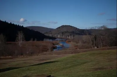a river in the middle of a field next to a mountain at Smith's Colonial Motel in Hancock