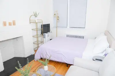 a white bedroom with a bed and a chair at Stylish East Village Apartment12 close to Union Square Steps from NYC Best Restaurants & Shops in New York