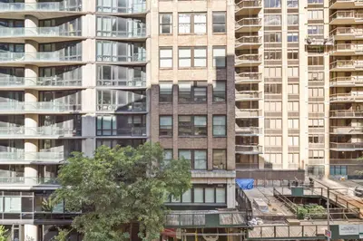 a tall apartment building with a tree in front of it at Blueground Midtown East rooftop nr Bryant Park NYC-2070 in New York