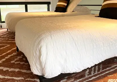 two beds with white comforters on top of a carpet at Tioga Ridge Lookout I Near Tioga-Hammond Lake