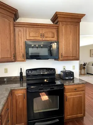 a kitchen with wooden cabinets and a black stove top oven at 11-Acre Retreat I Firepit, Pickleball and Nature
