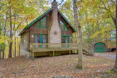 a log cabin in the woods with a green door at Year-Round Outdoor Adventures Poconos Hideaway in East Stroudsburg