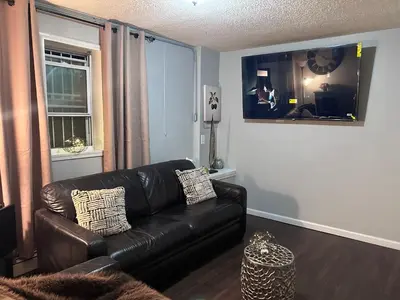 a living room with a black leather couch and a window at The Layover Lounge in Elizabeth