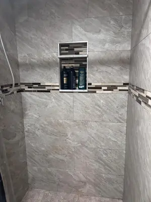 a bathroom with a tile shower with a shelf at The Layover Lounge in Elizabeth