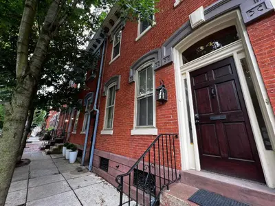 a red brick house with a red door on a street at THE WINTER HOUSE - HISTORIC DOWNTOWN LANCASTER in Lancaster