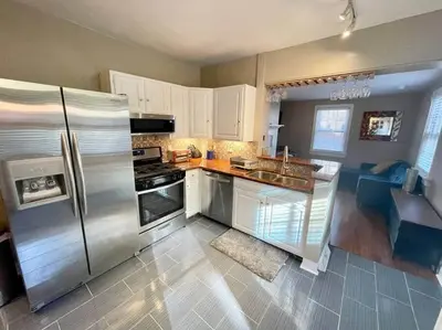 a kitchen with white cabinets and a stainless steel refrigerator at THE HANNAH HOUSE - DOWNTOWN HISTORIC LANCASTER in Lancaster