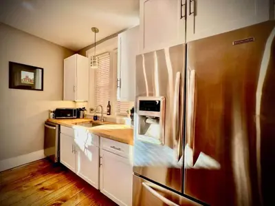 a kitchen with a stainless steel refrigerator and white cabinets at THE STAGE HOUSE - CITY CENTER THEATER DISTRICT in Lancaster