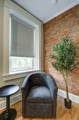 a chair in a living room with a brick wall at THE HAMILTON HOUSE - DOWNTOWN COLONIAL LANCASTER in Lancaster