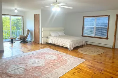 a bedroom with a bed and a chair and a window at Honesdale in Honesdale