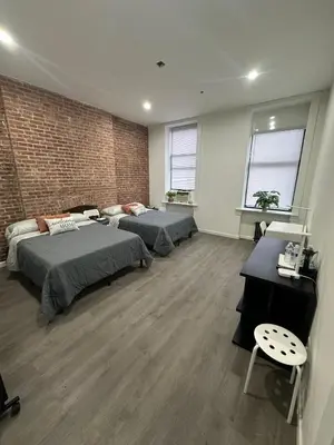 a bedroom with two beds and a brick wall at Aycee 417 in New York