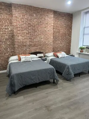 two beds in a room with a brick wall at Aycee 417 in New York