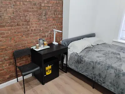 a bedroom with a bed and a desk and a brick wall at Aycee 417 in New York