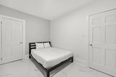a bed in a room with two white doors at 5MIN walk NYC Train Massage Chair Sleeps 12Plus in Bayonne