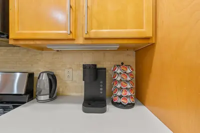 a kitchen counter with a coffee maker on the counter at 5MIN walk NYC Train Massage Chair Sleeps 12Plus in Bayonne
