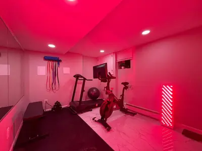 a room with a gym with a treadmill and red lights at 5MIN walk NYC Train Massage Chair Sleeps 12Plus in Bayonne