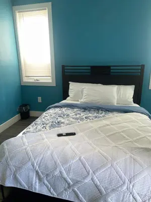 a blue bedroom with a bed with a remote control on it at Peace Sterling Haven in Newark