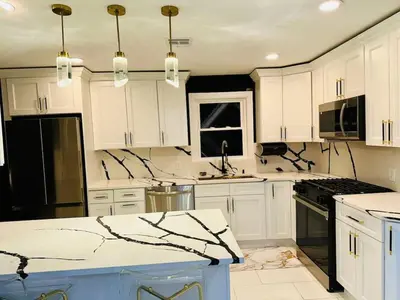 a kitchen with white cabinets and black appliances at 3 Large Bedroom Designer house Spacious in Newark