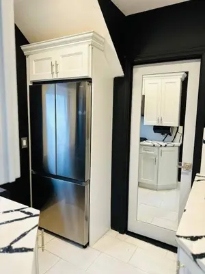 a kitchen with a stainless steel refrigerator and white cabinets at 1 Large Bedroom Contemporary Luxe Stay in Newark