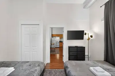 a white bedroom with two beds and a television at Large 1 BR in Center City with Double Queen Beds and King Sleeper Sofa) in Philadelphia