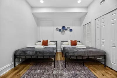 two beds in a room with white walls and wood floors at Brand New 2BR in the Heart of Center City that Sleeps 14 people in Philadelphia