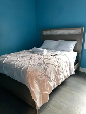 a bed in a bedroom with a blue wall at Peace Haven Stay in Newark