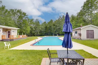 a blue umbrella sitting on a table next to a pool at Lakefront Pocono Retreat with Hot Tub and Movie Hub in Pocono Summit