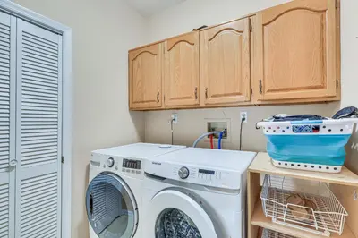 a laundry room with a washing machine and wooden cabinets at 5 Mi to Princeton Family Home with Deck and Yard! in Dutch Neck