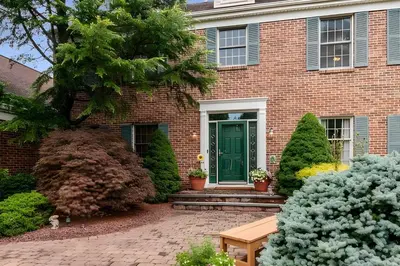 a brick house with a green door at 5 Mi to Princeton Family Home with Deck and Yard! in Dutch Neck