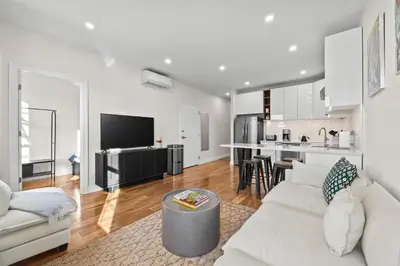a living room with a white couch and a kitchen at Carroll Place - Bright 3BR Apt in Carroll Gardens in Brooklyn