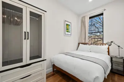 a white bedroom with a bed and a window at Carroll Place - Bright 3BR Apt in Carroll Gardens in Brooklyn