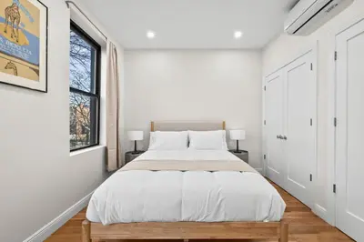 a white bedroom with a bed and a window at Carroll Place - Bright 3BR Apt in Carroll Gardens in Brooklyn