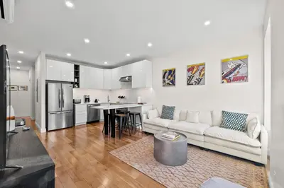 a white living room with a couch and a kitchen at Carroll Place - Bright 3BR Apt in Carroll Gardens in Brooklyn